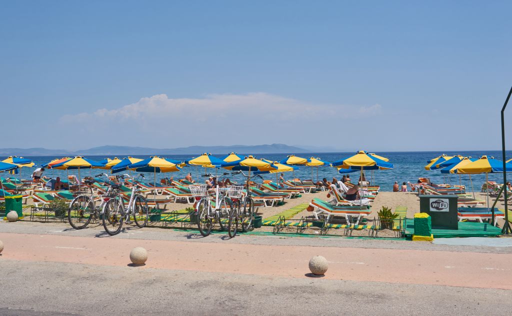 Photo of beach umbrellas, sun loungers and tourists on a Beach on Kos Island in Greece in early May