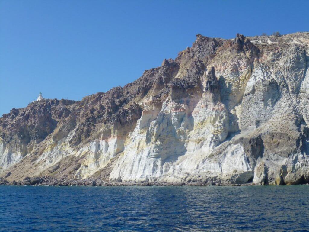 Photo of the white cliffs of Akrotiri and the Akrotiri ligthhouse from sea while sailing