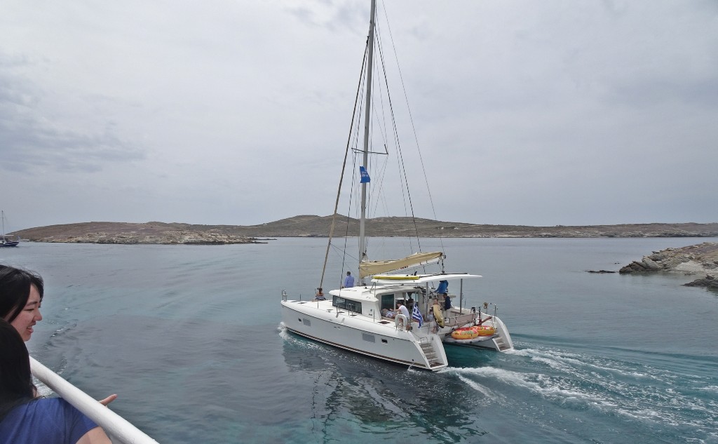 Private catamaran cruise leaving Delos Island, Greece